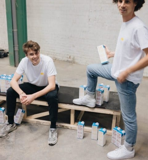 Men sitting and standing holding carton