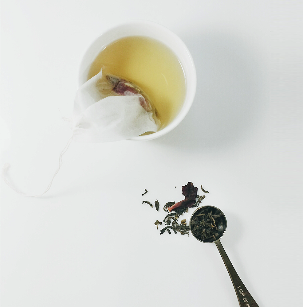 Mug with tea and tea leaves in tea filter bag plus spoon with tea leaves